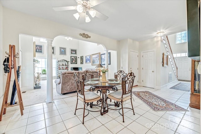 tiled dining space featuring decorative columns, plenty of natural light, and ceiling fan