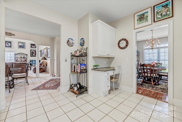 kitchen featuring light wood-type flooring, white cabinets, pendant lighting, and a chandelier