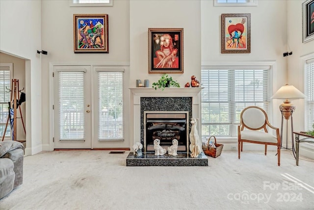 living room featuring a towering ceiling, carpet floors, french doors, and a fireplace