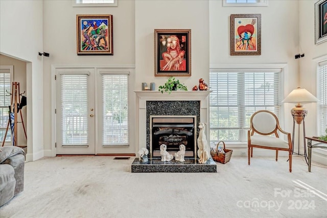 living area featuring visible vents, carpet floors, a high ceiling, and a fireplace