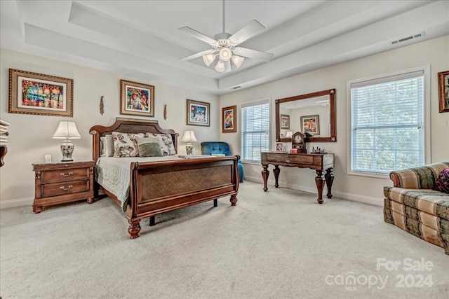 carpeted bedroom featuring a raised ceiling and ceiling fan