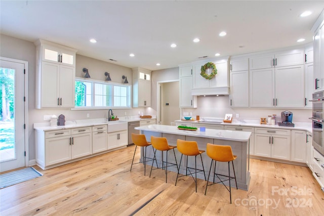 kitchen with a kitchen breakfast bar, light hardwood / wood-style flooring, appliances with stainless steel finishes, and a kitchen island