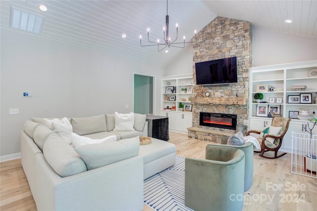 living room with high vaulted ceiling, built in shelves, a fireplace, a chandelier, and light hardwood / wood-style floors