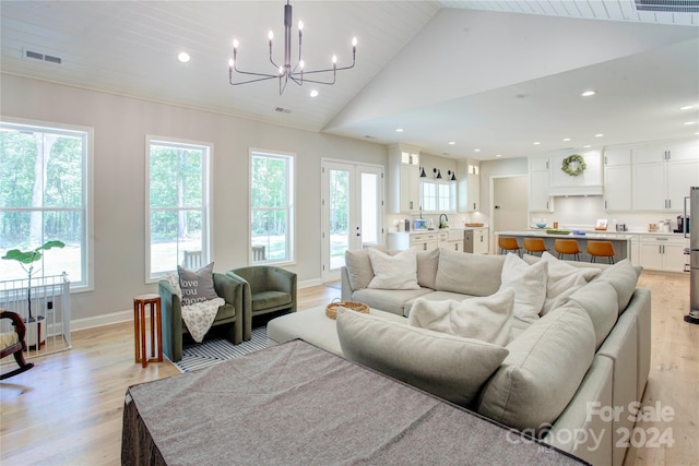 living room with sink, light hardwood / wood-style flooring, high vaulted ceiling, and a chandelier