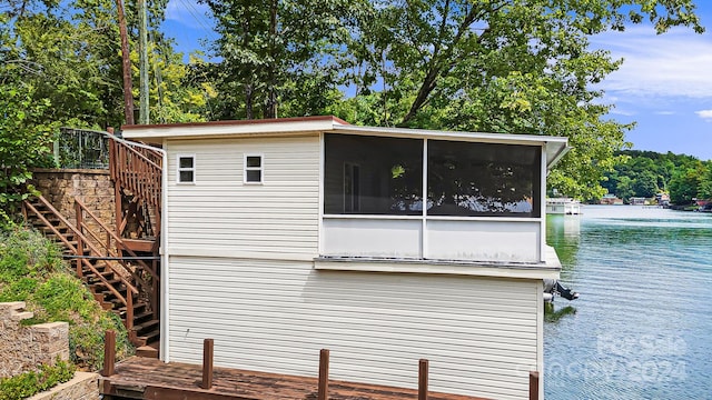 view of side of property with a sunroom and a deck with water view