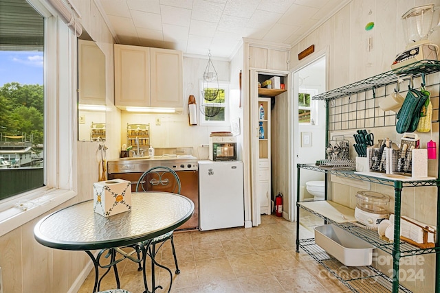 kitchen with light tile patterned floors, a healthy amount of sunlight, and ornamental molding