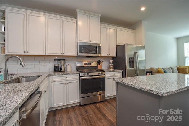 kitchen with sink, tasteful backsplash, dark hardwood / wood-style floors, white cabinets, and appliances with stainless steel finishes