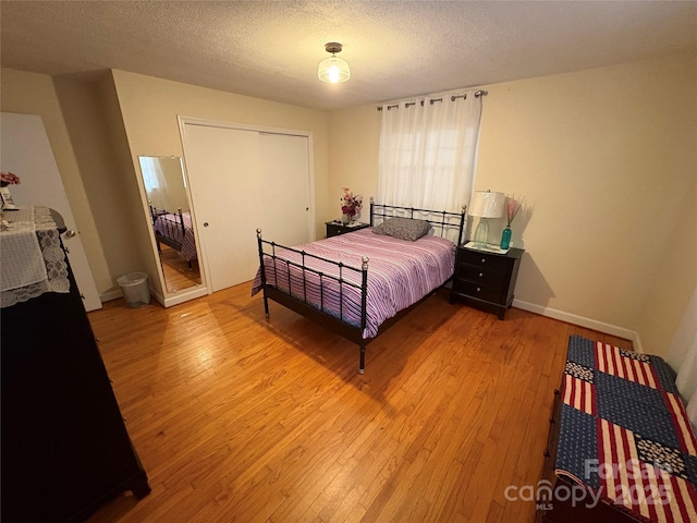 bedroom with light wood-style floors, a closet, and a textured ceiling