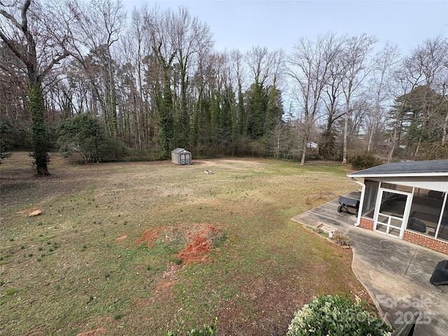 view of yard featuring an outbuilding, a shed, and a patio area