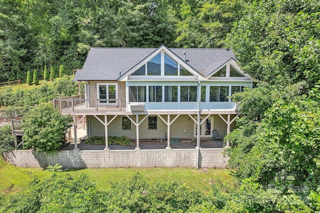 back of property with a deck, a yard, a sunroom, and a shingled roof