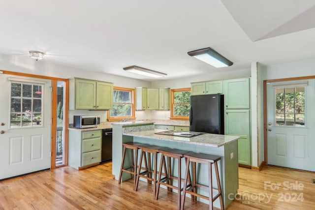 kitchen featuring light wood-type flooring, a breakfast bar area, a kitchen island, and black appliances