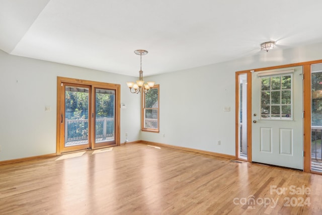 unfurnished dining area with light hardwood / wood-style floors and an inviting chandelier