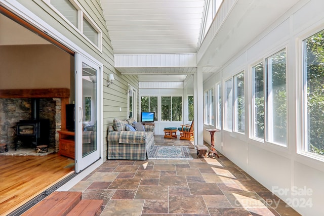 sunroom / solarium with a healthy amount of sunlight and a wood stove