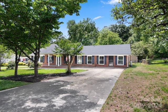 ranch-style house featuring concrete driveway, brick siding, fence, and a front yard