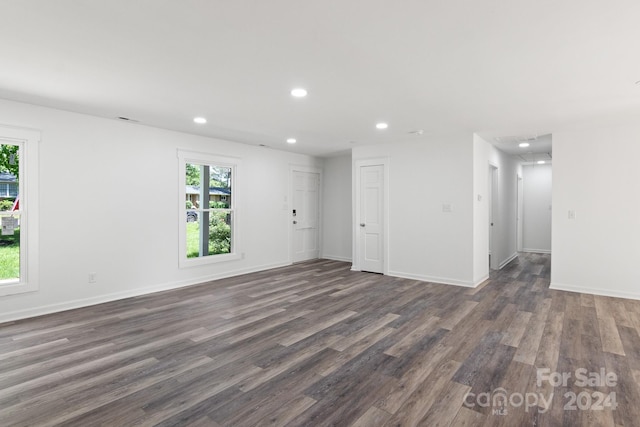 unfurnished living room with baseboards, recessed lighting, dark wood-type flooring, and a healthy amount of sunlight