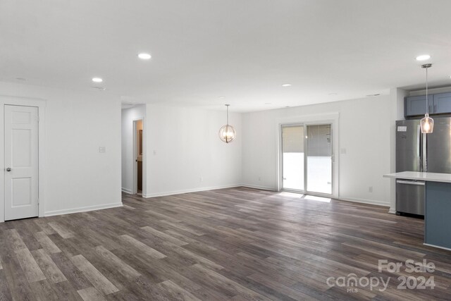 unfurnished living room with baseboards, a notable chandelier, dark wood-type flooring, and recessed lighting