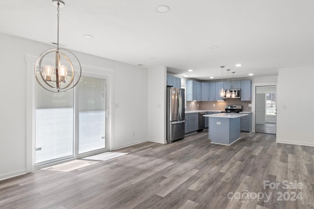 kitchen with a center island, decorative light fixtures, wood-type flooring, tasteful backsplash, and stainless steel appliances