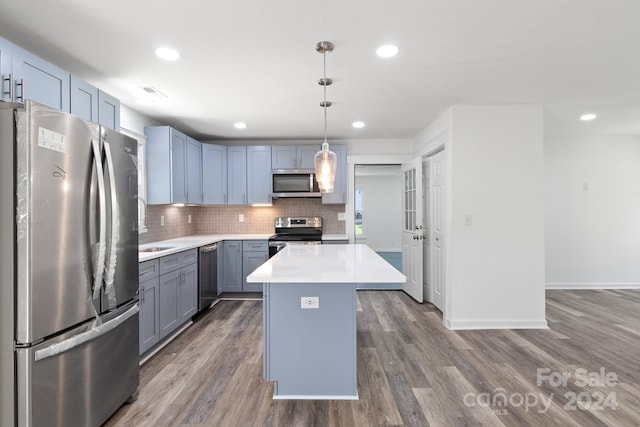 kitchen with tasteful backsplash, hanging light fixtures, hardwood / wood-style floors, a center island, and stainless steel appliances