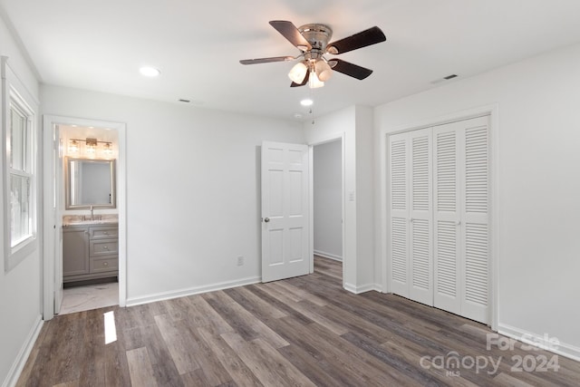 unfurnished bedroom featuring ceiling fan, a closet, connected bathroom, and hardwood / wood-style flooring