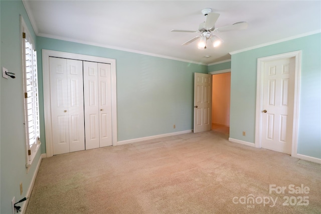 unfurnished bedroom featuring a closet, light colored carpet, ceiling fan, and crown molding