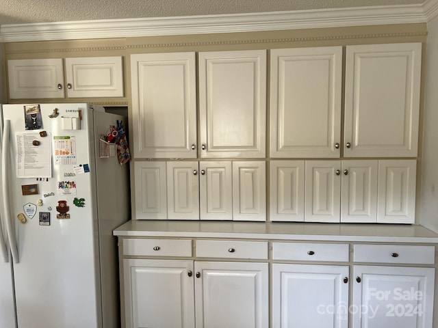 kitchen featuring a textured ceiling, crown molding, white cabinets, and white fridge