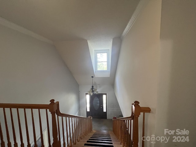 staircase with lofted ceiling, ornamental molding, and an inviting chandelier