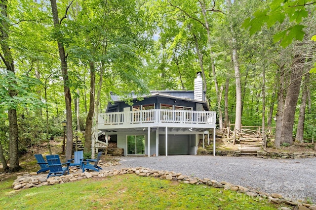 back of house featuring an outdoor fire pit, driveway, a chimney, and a wooden deck