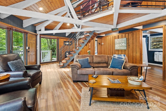 living room with wood walls, light hardwood / wood-style flooring, wooden ceiling, and lofted ceiling with beams