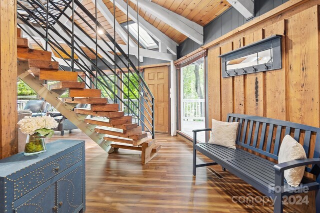 interior space featuring wood walls, plenty of natural light, vaulted ceiling with beams, and hardwood / wood-style floors