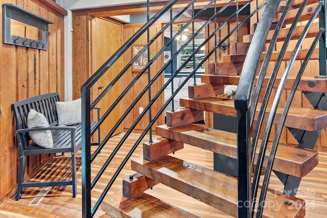 stairs with wood walls and wood finished floors