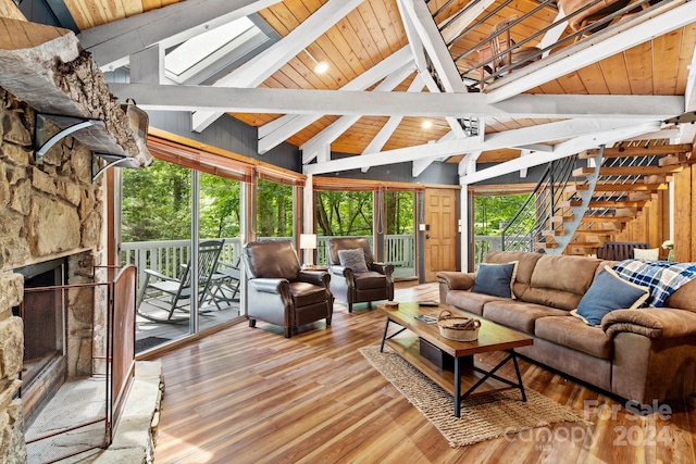 sunroom with wood ceiling, a stone fireplace, and lofted ceiling with beams