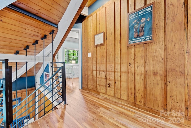 interior space featuring wooden ceiling, wood finished floors, an upstairs landing, and wooden walls