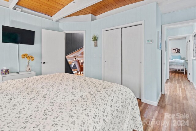 bedroom featuring a closet, beamed ceiling, light hardwood / wood-style floors, and wooden ceiling