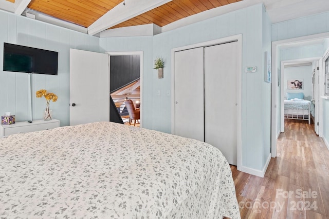 bedroom with wood ceiling, a closet, light wood-type flooring, and beam ceiling