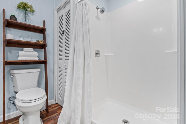 bathroom with toilet, hardwood / wood-style flooring, and curtained shower