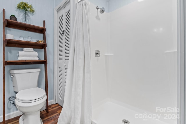 full bath featuring curtained shower, wood finished floors, and toilet