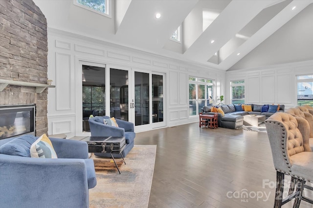 living room with hardwood / wood-style floors, plenty of natural light, high vaulted ceiling, and french doors