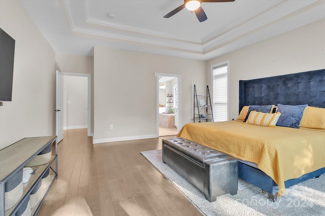 bedroom featuring wood-type flooring, connected bathroom, a raised ceiling, and ceiling fan