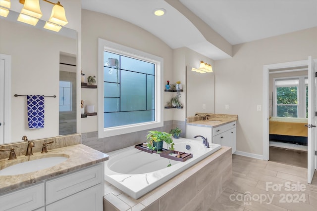 bathroom with tile patterned flooring, vanity, and a relaxing tiled tub