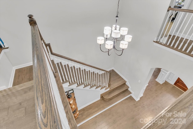 staircase with hardwood / wood-style flooring and a notable chandelier