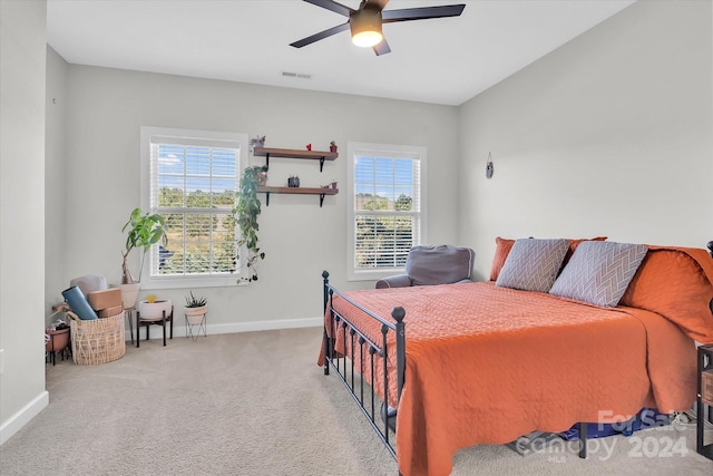 bedroom featuring light colored carpet, multiple windows, and ceiling fan