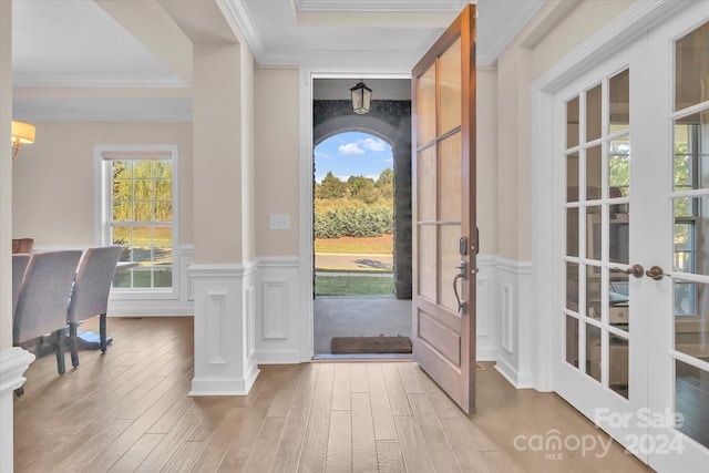 entrance foyer with crown molding, french doors, and light hardwood / wood-style flooring