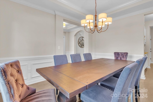 dining area featuring light hardwood / wood-style flooring, ornamental molding, and an inviting chandelier