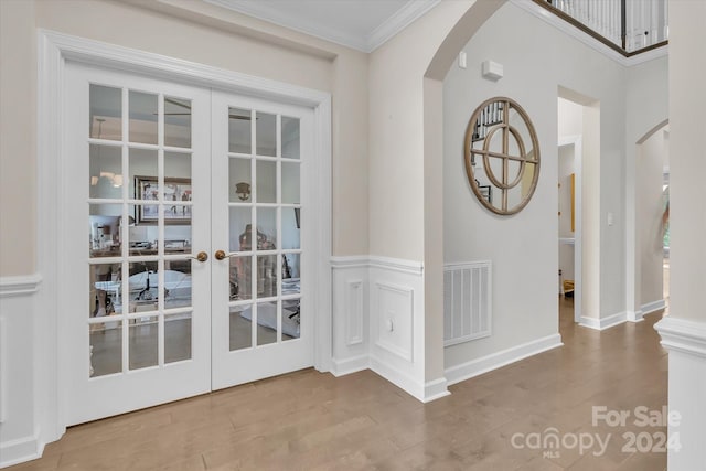 doorway with hardwood / wood-style floors, crown molding, and french doors