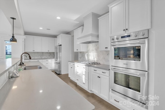 kitchen with sink, stainless steel appliances, pendant lighting, white cabinets, and custom exhaust hood