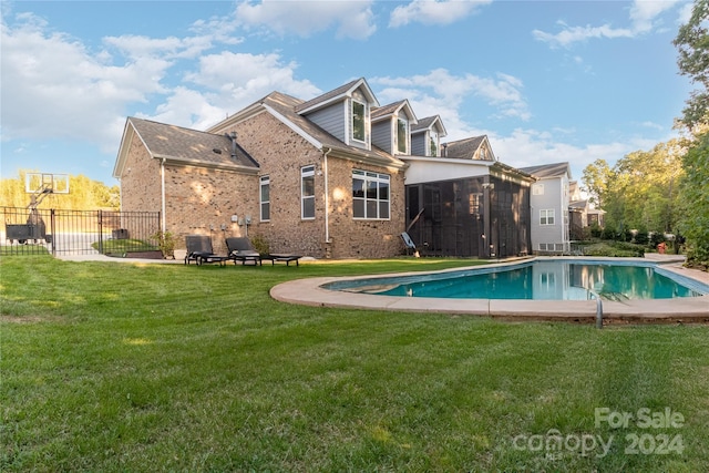 back of house featuring a fenced in pool, a lawn, and a sunroom