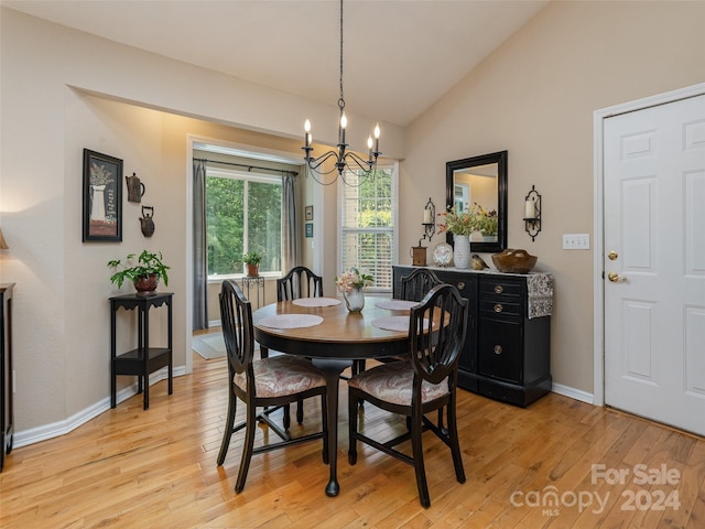 dining area with a notable chandelier, light hardwood / wood-style floors, and lofted ceiling