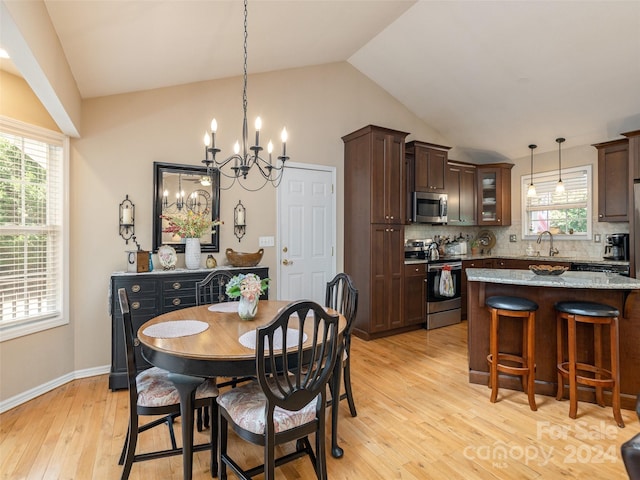 dining room with sink, an inviting chandelier, light hardwood / wood-style flooring, and lofted ceiling