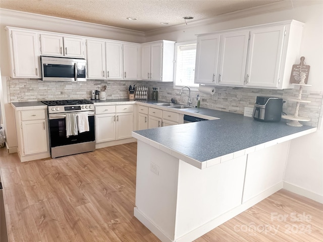 kitchen featuring light wood-type flooring, appliances with stainless steel finishes, white cabinetry, sink, and kitchen peninsula