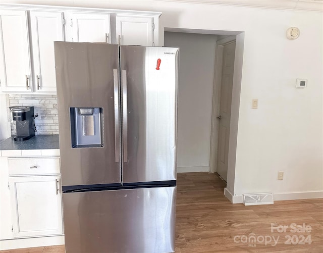 kitchen with stainless steel fridge with ice dispenser, white cabinetry, and light hardwood / wood-style flooring